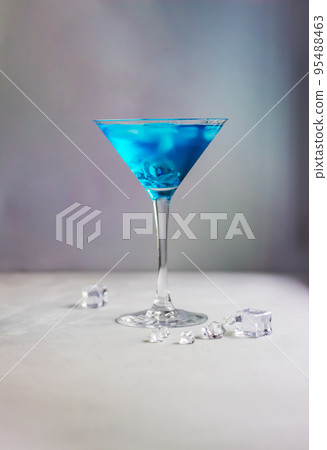 Blue cocktail in martini glass with ice cubes 95488463