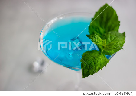 Close-up of blue cocktail in martini glass with ice cubes and mint Close-up of blue cocktail in martini glass with ice cubes and mint 95488464