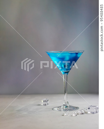 Blue cocktail in martini glass with ice cubes 95488485