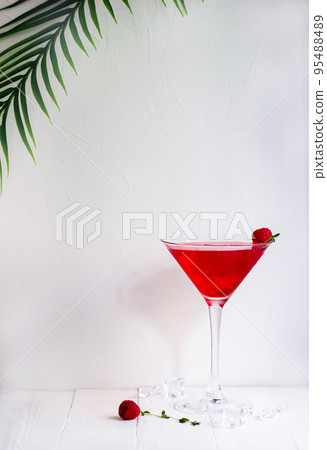 Red alcohol cocktail with raspberries and thyme on the white wood table. 95488489
