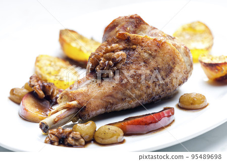 poultry leg baked with fruit and walnuts served with fried potatoes 95489698