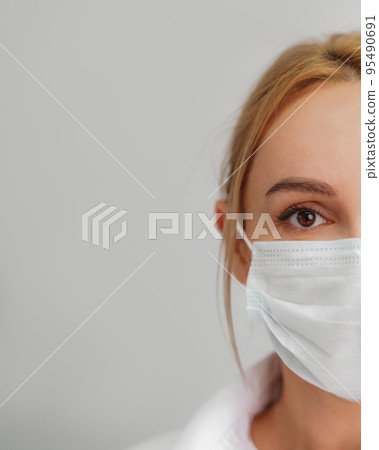 Close-up portrait of a young blonde woman in a medical mask on a light background. Virus protection. Coronovirus covid-19 The concept of a pandemic epidemic. Quarantine. Stay at home. Close-up portrait of a young blonde woman in a medical mask on a light background. Virus protection. Coronovirus covid-19 The concept of a pandemic epidemic. Quarantine. Stay at home. 95490691