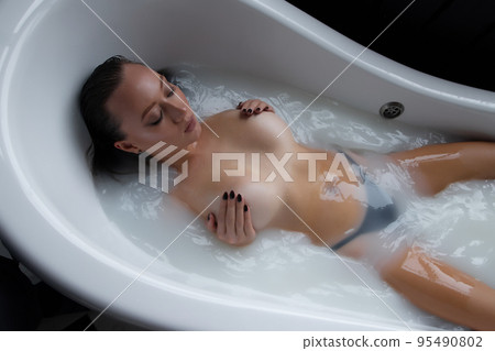 Topless sexy female in milk water in tub Topless sexy female in milk water in tub 95490802