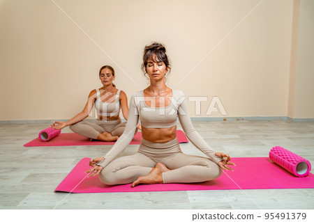 Two young women meditating in Lotus Pose. Padmasan Two young women meditating in Lotus Pose. Padmasan 95491379