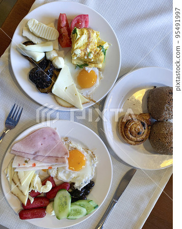 Lunch. Plates of eggs, ham, cheese and vegetables on table. Studio Photo Lunch. Plates of eggs, ham, cheese and vegetables on table. Studio Photo 95491997