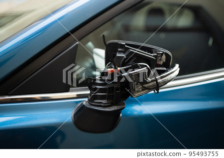 Closeup of a side broken rearview mirror of a new blue car, fixed with tape. City road accident 95493755