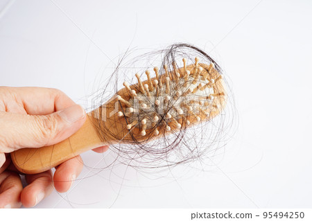 Asian woman have problem with long hair loss attach to comb brush. 95494250