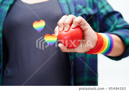 Asian woman holding red hert with rainbow flag, LGBT symbol rights and gender equality, LGBT Pride Month in June. Asian woman holding red hert with rainbow flag, LGBT symbol rights and gender equality, LGBT Pride Month in June. 95494383