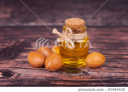 Argan oil on wooden background. Argan nuts and seeds, for cosmetic and beauty products. Natural argan fruit from Morocco. 95494508