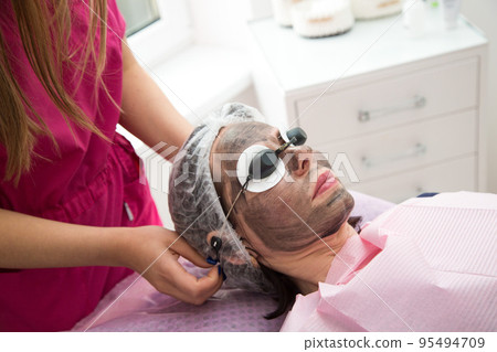 Portrait of an adult woman lying with her eyes closed during the carbon peeling procedure Portrait of an adult woman lying with her eyes closed during the carbon peeling procedure 95494709