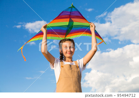 The girl alone launches a multicolored kite into the sky The girl alone launches a multicolored kite into the sky 95494712