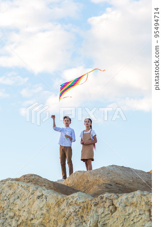 Classmates a boy and a girl launch a kite standing on the edge of the abyss Classmates a boy and a girl launch a kite standing on the edge of the abyss 95494714