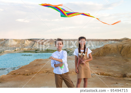 Classmates a boy and a girl launch a kite standing on the edge of the abyss Classmates a boy and a girl launch a kite standing on the edge of the abyss 95494715
