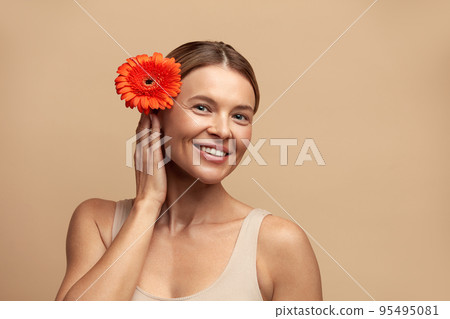 Skin Care Woman Posing with Red Flower. Model Holding Flower Looking At Camera Skin Care Woman Posing with Red Flower. Model Holding Flower Looking At Camera 95495081
