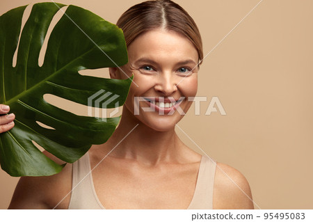 Skin Care Woman Posing with Green Leaf. Caucasian Model Holding Tropical Plant Skin Care Woman Posing with Green Leaf. Caucasian Model Holding Tropical Plant 95495083