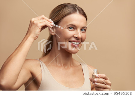 Woman Applying Serum on Face. Woman Applying Essential Oil On Facial Skin 95495108