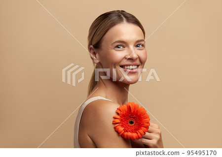 Skin Care Woman Posing with Red Flower. Model Holding Flower Looking At Camera Skin Care Woman Posing with Red Flower. Model Holding Flower Looking At Camera 95495170