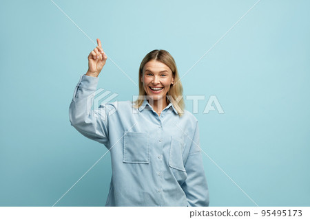 Cheerful Woman Pointing Up at Studio. Overjoyed Girl Points Finger Empty Space 95495173