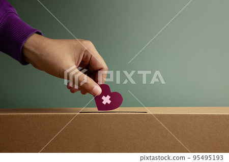 Donation Concept. Hand Drop a Paper Heart with Cross into a Donate Box. Helping, Supporting and Togetherness. Side View 95495193