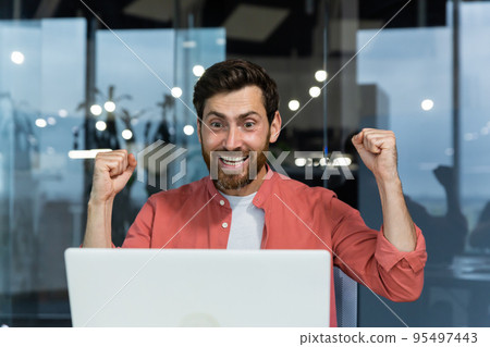 Close up of successful businessman, man celebrating victory and successful triumph, looking at laptop screen reading good news and happy holding hands up, winner gesture Close up of successful businessman, man celebrating victory and successful triumph, looking at laptop screen reading good news and happy holding hands up, winner gesture 95497443