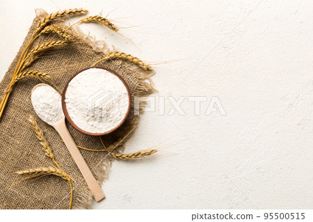 Flat lay of Wheat flour in wooden bowl with wheat spikelets on colored background. world wheat crisis 95500515