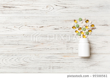 Multicolored pills and capsules in plastic bottle on Colored background, copy space. Many different various medicine tablets and pills, vitamin and nutritional supplements concept 95500561
