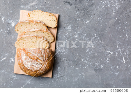 Freshly baked bread slices on cutting board against white wooden background. top view Sliced bread 95500608