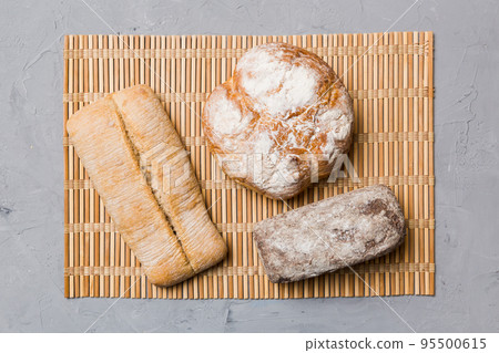 Assortment of freshly baked bread with napkin on rustic table top view. Healthy unleavened bread. French bread Assortment of freshly baked bread with napkin on rustic table top view. Healthy unleavened bread. French bread 95500615