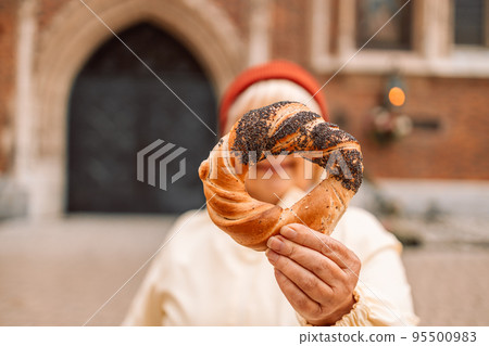 Senior woman holding prezel, traditional polish snack on the Market square in Krakow Senior woman holding prezel, traditional polish snack on the Market square in Krakow 95500983