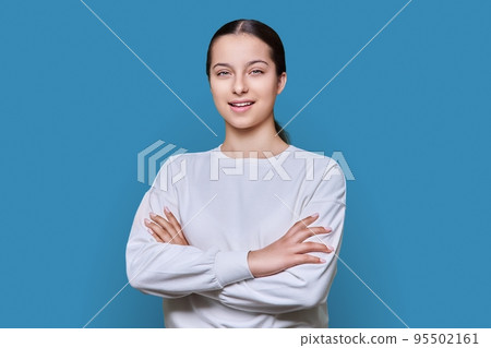 Portrait of smiling teenage girl looking at camera on blue studio background Portrait of smiling teenage girl looking at camera on blue studio background 95502161
