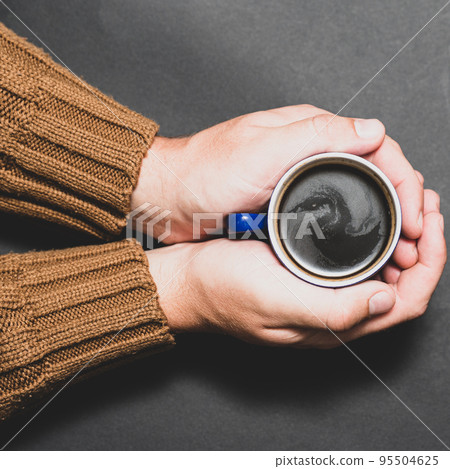 Male hands hold coffee on a dark background. 95504625