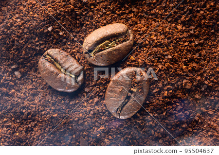 Three coffee beans lie on ground coffee close-up. Three coffee beans lie on ground coffee close-up. 95504637