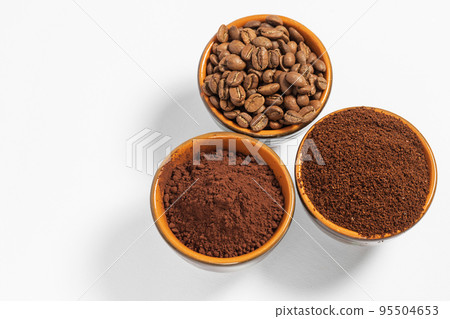 Cups with roasted coffee beans and ground coffee, white background and copy space. Cups with roasted coffee beans and ground coffee, white background and copy space. 95504653