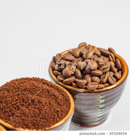 Cups with roasted coffee beans and ground coffee, white background and copy space. Cups with roasted coffee beans and ground coffee, white background and copy space. 95504654