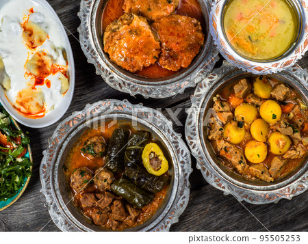 Eid Mubarak Traditional Ramadan Iftar dinner. Assorted tasty food in authentic rustic dishes on wooden blue background. Turkish Bosnian food meat kebab, pita, Sarma, klepe, sogan dolma. 95505253