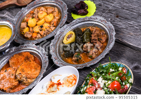 Eid Mubarak Traditional Ramadan Iftar dinner. Assorted tasty food in authentic rustic dishes on wooden blue background. Turkish Bosnian food meat kebab, pita, Sarma, klepe, sogan dolma. Eid Mubarak Traditional Ramadan Iftar dinner. Assorted tasty food in authentic rustic dishes on wooden blue background. Turkish Bosnian food meat kebab, pita, Sarma, klepe, sogan dolma. 95505315