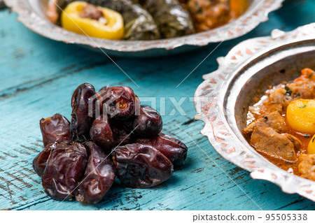 Eid Mubarak Traditional Ramadan Iftar dinner. Assorted tasty food in authentic rustic dishes on wooden blue background. Turkish Bosnian food meat kebab, pita, Sarma, klepe, sogan dolma. Eid Mubarak Traditional Ramadan Iftar dinner. Assorted tasty food in authentic rustic dishes on wooden blue background. Turkish Bosnian food meat kebab, pita, Sarma, klepe, sogan dolma. 95505338