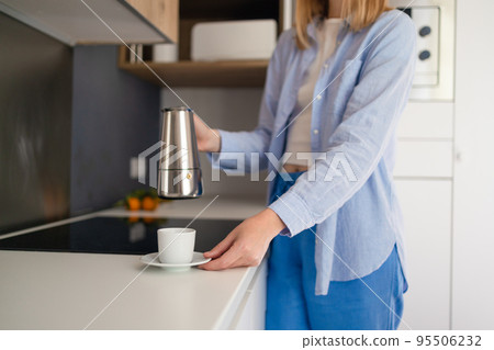 Cropped photo of a woman hands pouring coffee from a pot while standing in the kitchen. Having breakfast in the morning 95506232