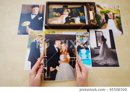 printed wedding photos in the hands and in a wooden box with a flash drive.  95506508