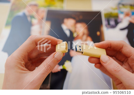 selective focus. printed wedding photos, wooden box and hands with flash drive selective focus. printed wedding photos, wooden box and hands with flash drive 95506510