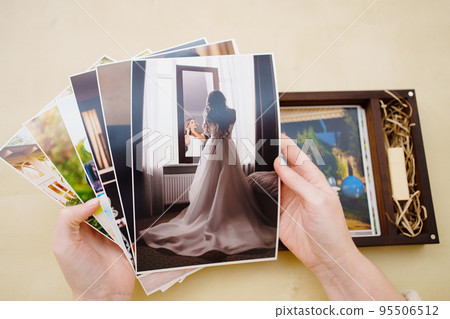 printed wedding photos in the hands and in a wooden box with a flash drive. printed wedding photos in the hands and in a wooden box with a flash drive. 95506512