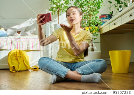 Teenage girl using smartphone for video call, room at home Teenage girl using smartphone for video call, room at home 95507228