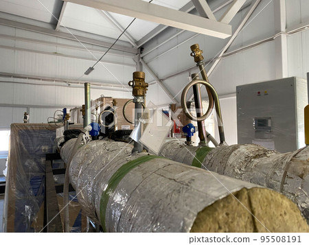 Pipes with tubes and flanges in silver mineral wool thermal insulation to save heat for pumping liquids in refinery petrochemical plant equipment 95508191