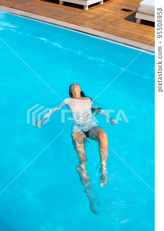 Sensual lady in wet dress standing in pool during summer vacation Sensual lady in wet dress standing in pool during summer vacation 95508958