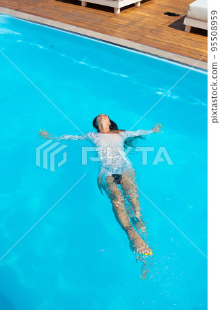 Sensual lady in wet dress standing in pool during summer vacation 95508959