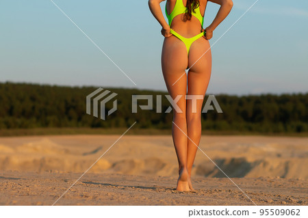 Crop sexy lady in bikini touching buttocks on sandy beach 95509062