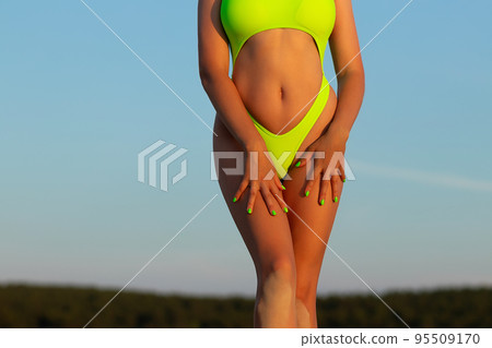 Crop sexual woman in swimsuit against sunset sky Crop sexual woman in swimsuit against sunset sky 95509170