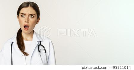 Frustrated and upset young woman, looking left with insulted shocked face, standing in doctor uniform over white background 95511014