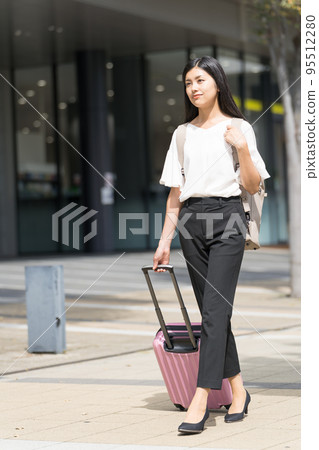 一個背著背包和手提箱走路的女商人 一個背著背包和手提箱走路的女商人 95512280