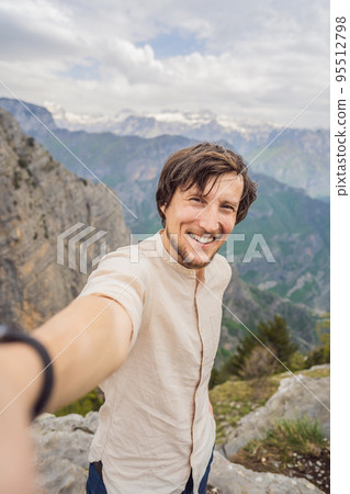 Man tourist on background of Breathtaking panoramic view of the Grlo Sokolovo gorge in Montenegro. In the foreground is a mountain, the flat side of which forms a cliff, and the ridge is overgrown 95512798